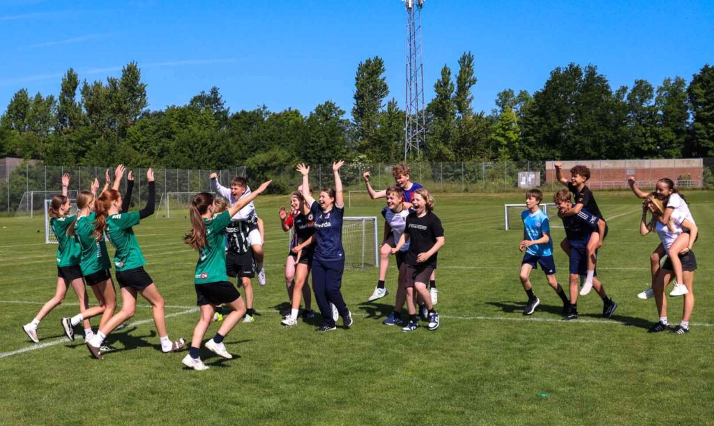 Elever i idrætsundervisning jubler på en græsplæne