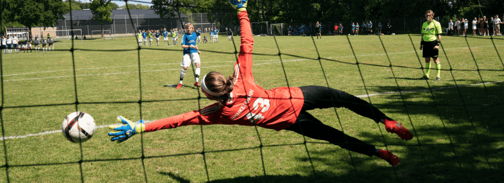 Målmand forsøger at redde bolden under en fodboldkamp.