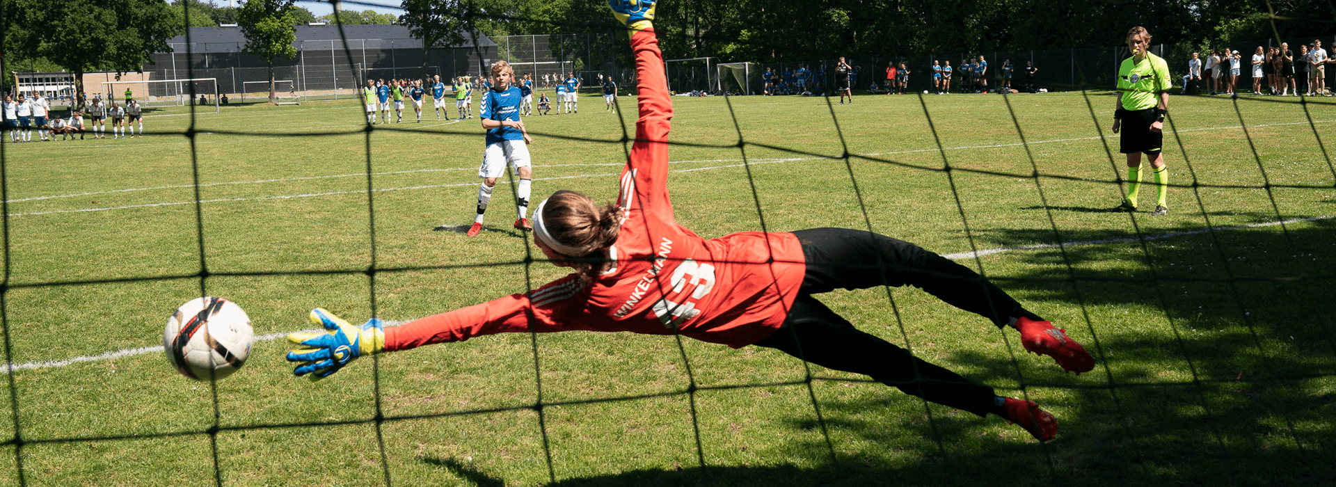 Målmand forsøger at redde bolden under en fodboldkamp.