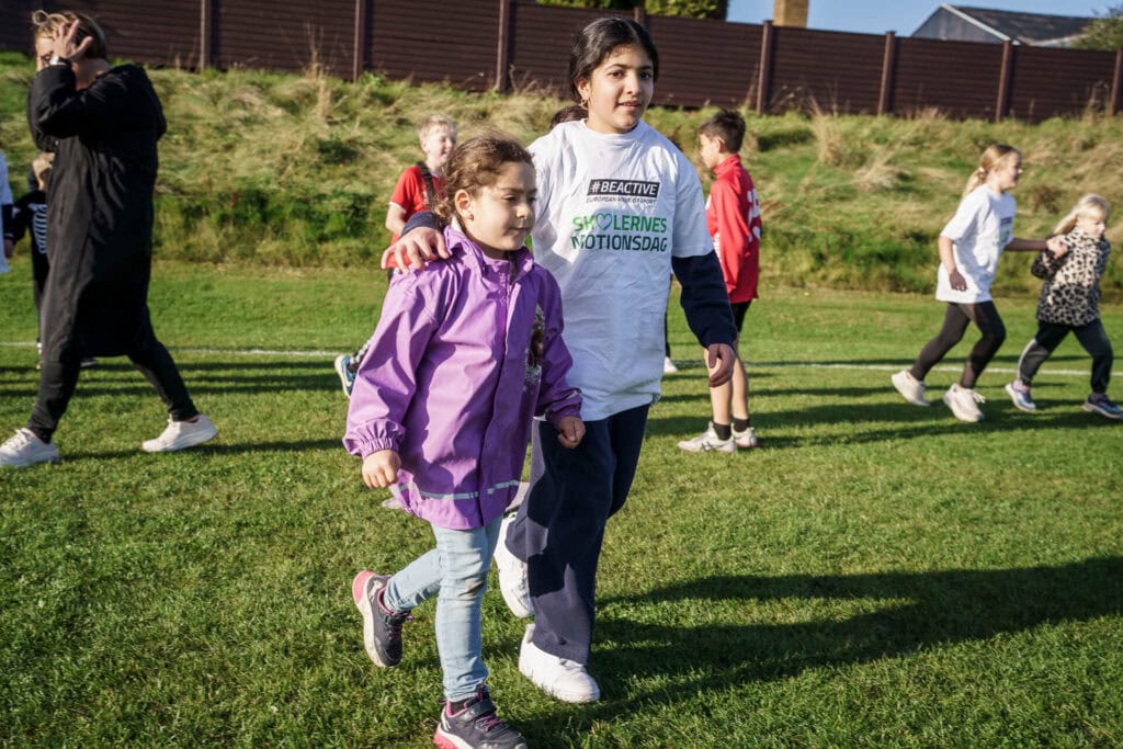 En stor elev løber med en lille elev i hånden