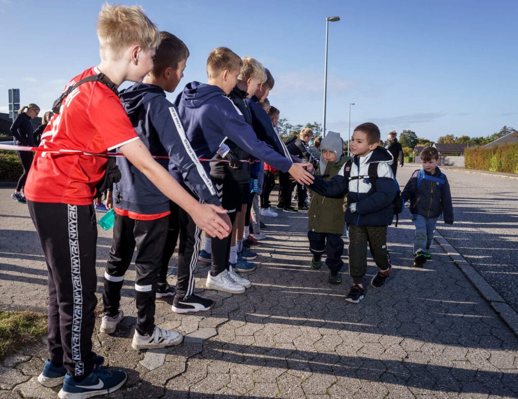 Række af børn giver highfives til mindre børn
