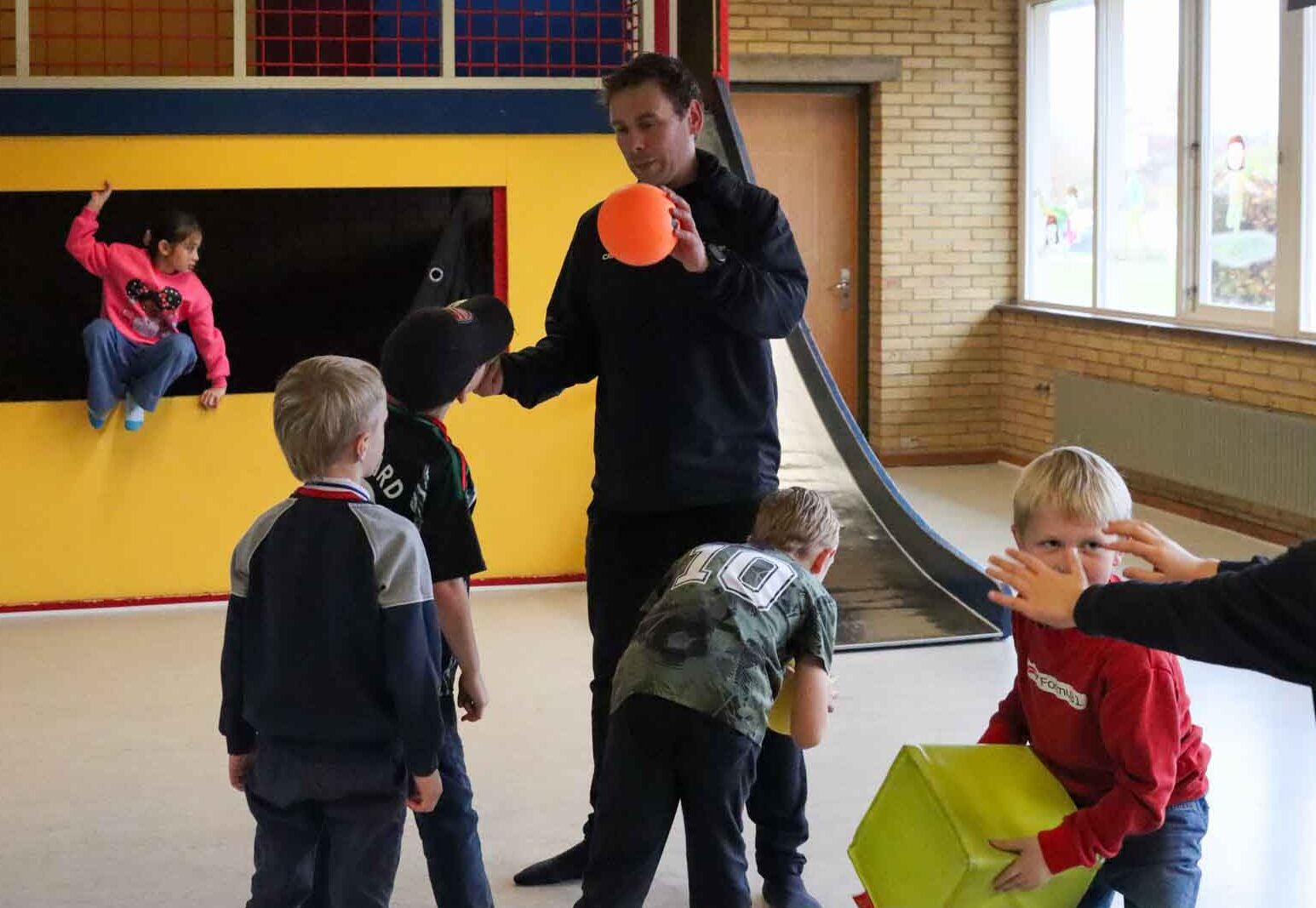 Voksen holder en bold leger med børn