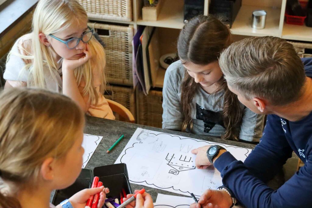 Projektleder sidder med børn og spørger ind til deres tegninger