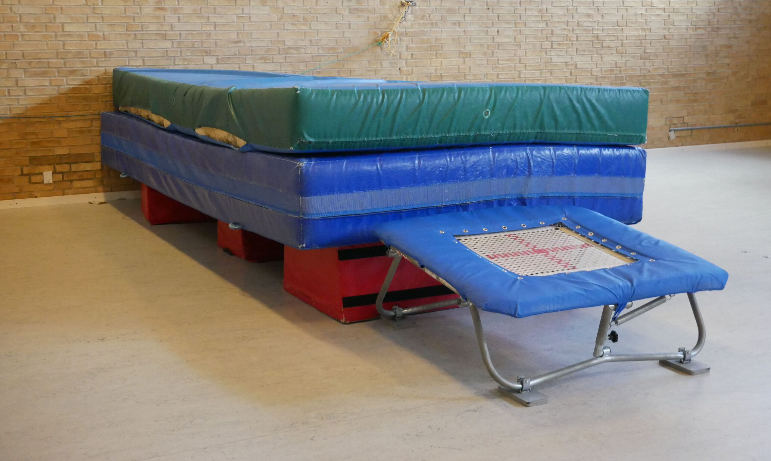 To tykmåtter og en trampolin i en gymnastiksal